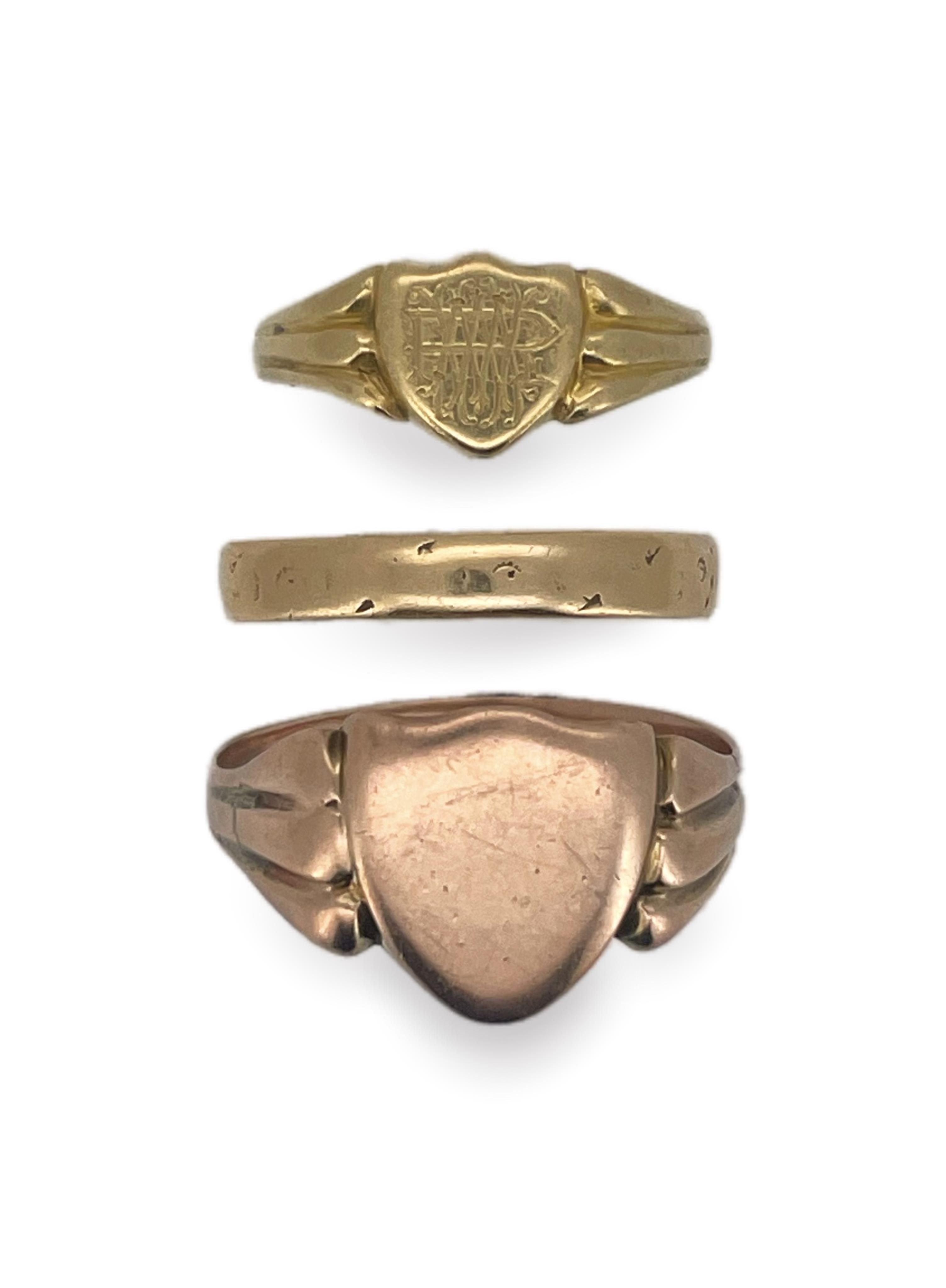 Three gold rings, comprising: a Victorian 18ct gold shield-shaped signet ring, bearing the monogram RMW, to a fluted band, size O, British hallmarks, gross weight approximately 3 grams; an 18ct gold wedding band, size R,